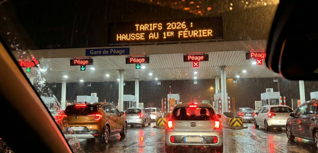 Barrière de péage autoroutier de nuit sous la pluie avec affichage tarifaire lumineux - Hausse tarifs 2026